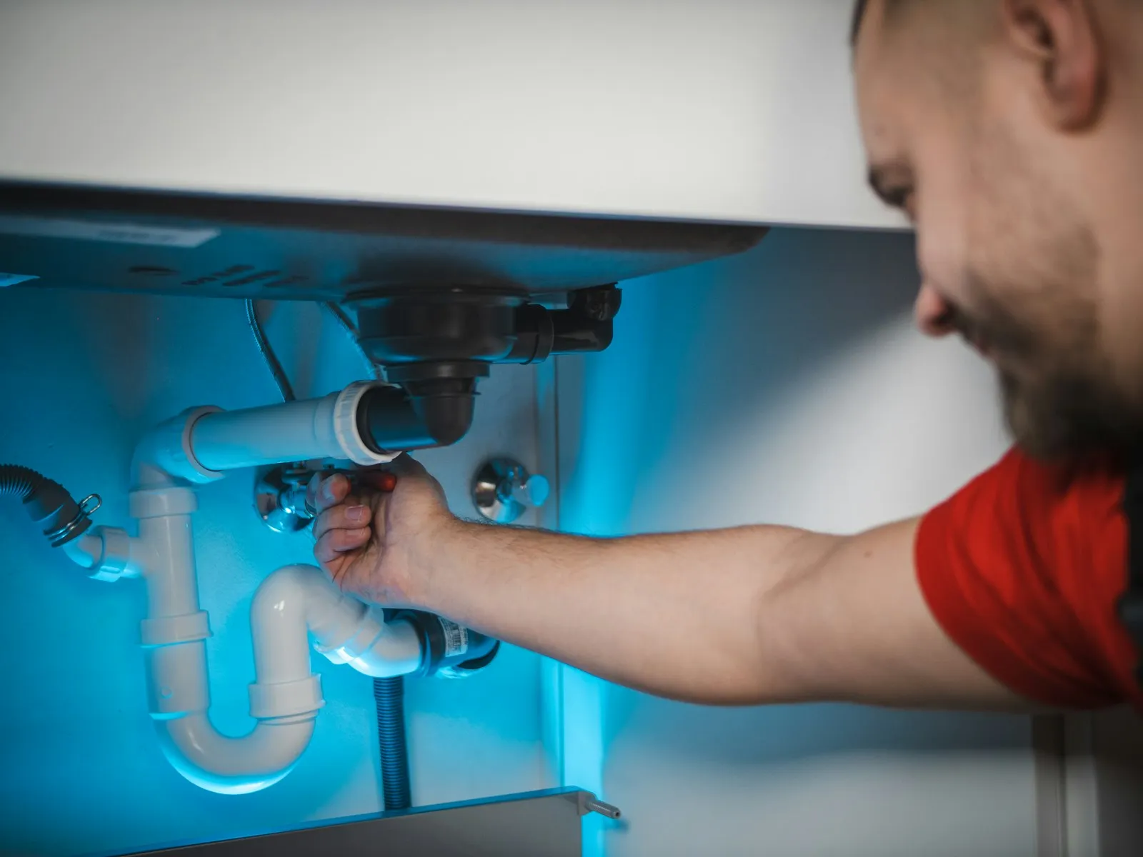 Instalator care repară scurgerea de sub o chiuvetă
